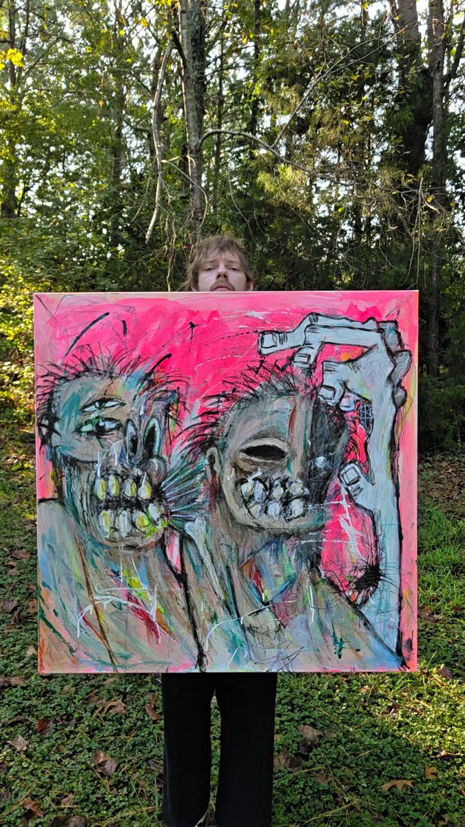 A person stands outdoors in a wooded area holding up a large, expressive painting with a pink background depicting two distorted faces and a grey hand.