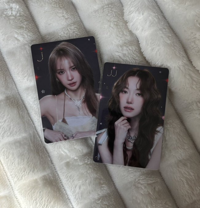 Two photocard portraits of a young woman with long dark hair, one labeled "J" and the other "JJ," resting on a fluffy cream-colored blanket.