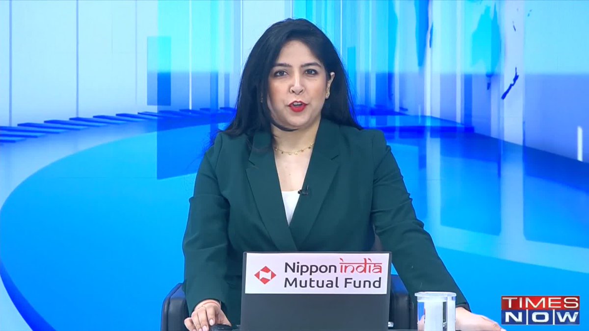 A female news anchor in a green blazer delivers a broadcast on Times Now, with a 'Nippon India Mutual Fund' logo displayed on the desk.