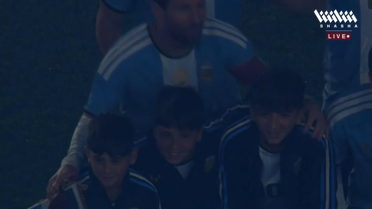 In this image, Argentina's coach Lionel Scaloni poses for a group photo with the national team players, including Lionel Messi, celebrating their victory, with the "SHASHA LIVE" logo visible in the upper right corner, capturing the triumphant "Wow!" sentiment.