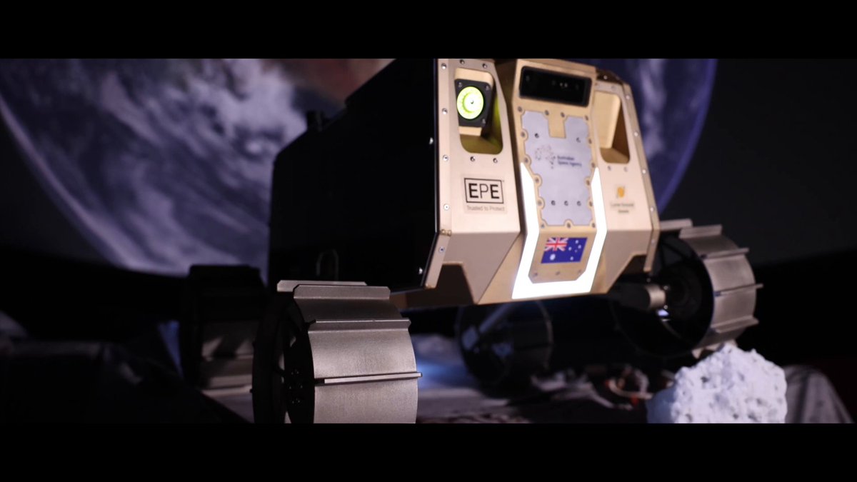 A small lunar rover labeled 'EPE' with an Australian flag decal sits on a rocky surface with the Earth visible in the dark background.