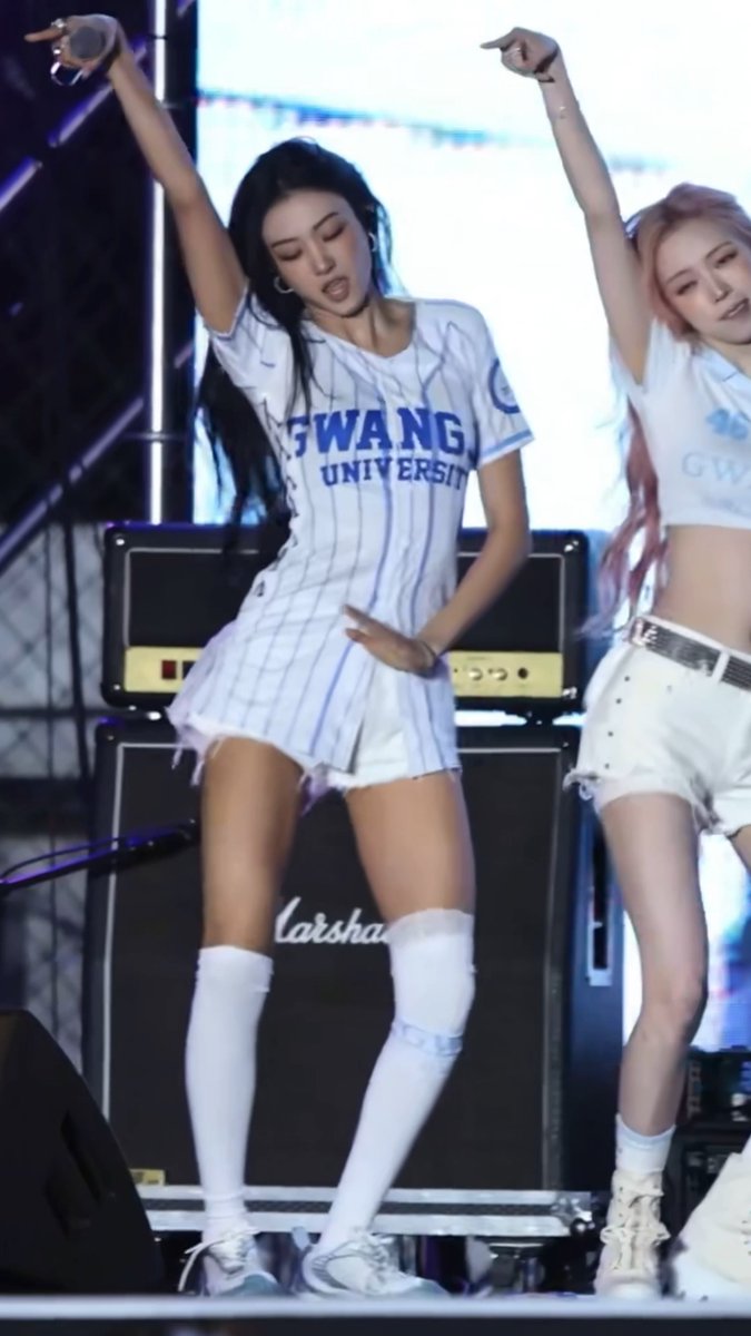 Two female performers dance on stage wearing white outfits with 'GWANG UNIVERSITY' printed on the jerseys.