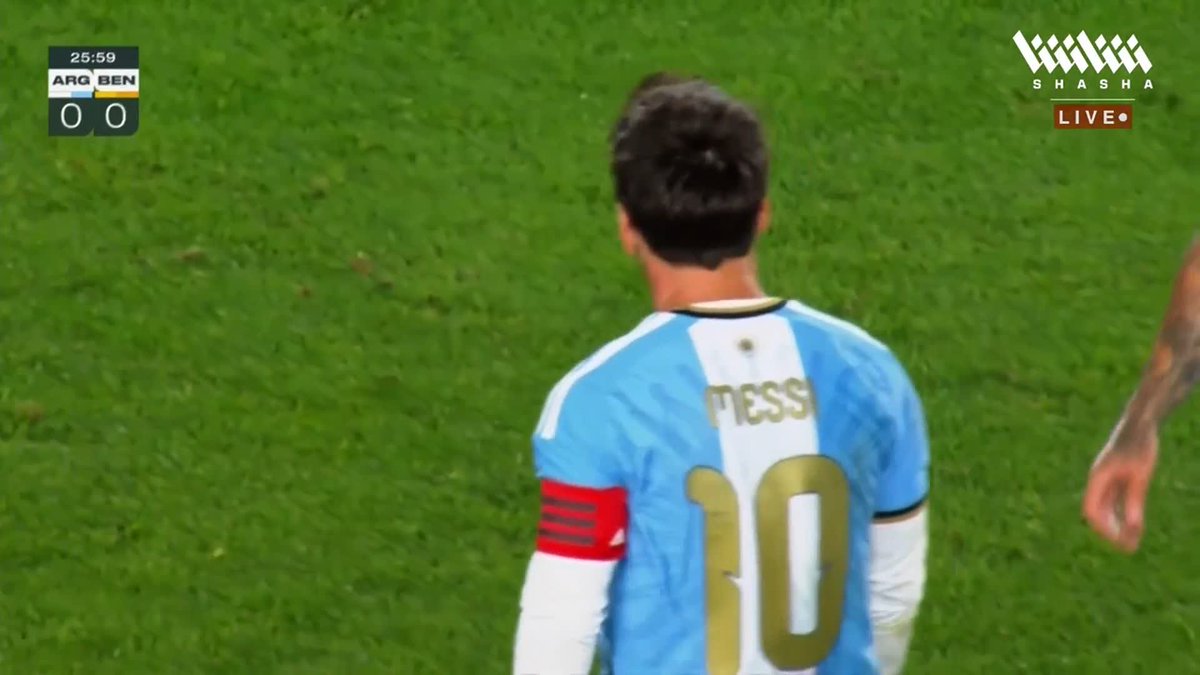 Lionel Messi, wearing the iconic Argentina #10 jersey with captain's armband, is shown from behind on the pitch during his retirement match against Benin, with the score still 0-0 at the 25:59 mark as broadcast on Shasha Live.