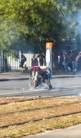 altrella_l's tweet photo. The iconic image from the protests in France: a young man in a wheelchair is hit by tear gas canisters fired by the police, picks them up, and throws them back at the police. ✊ https://t.co/AAWoku0kj5