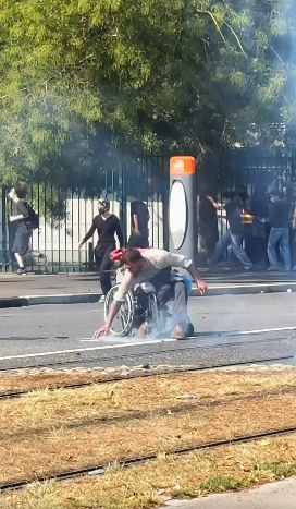 altrella_l's tweet photo. The iconic image from the protests in France: a young man in a wheelchair is hit by tear gas canisters fired by the police, picks them up, and throws them back at the police. ✊ https://t.co/AAWoku0kj5
