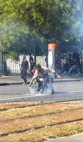 altrella_l's tweet photo. The iconic image from the protests in France: a young man in a wheelchair is hit by tear gas canisters fired by the police, picks them up, and throws them back at the police. ✊ https://t.co/AAWoku0kj5