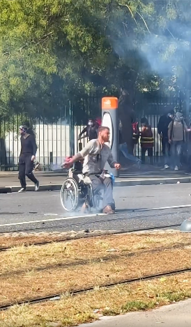 altrella_l's tweet photo. The iconic image from the protests in France: a young man in a wheelchair is hit by tear gas canisters fired by the police, picks them up, and throws them back at the police. ✊ https://t.co/AAWoku0kj5