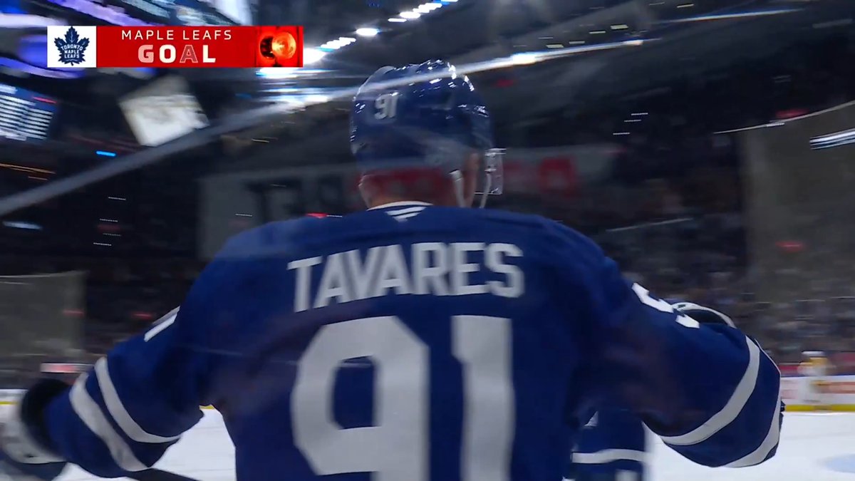 A blurry action shot from a hockey broadcast showing Maple Leafs player Tavares (#91) from behind, with a 'MAPLE LEAFS GOAL' graphic in the upper left corner.