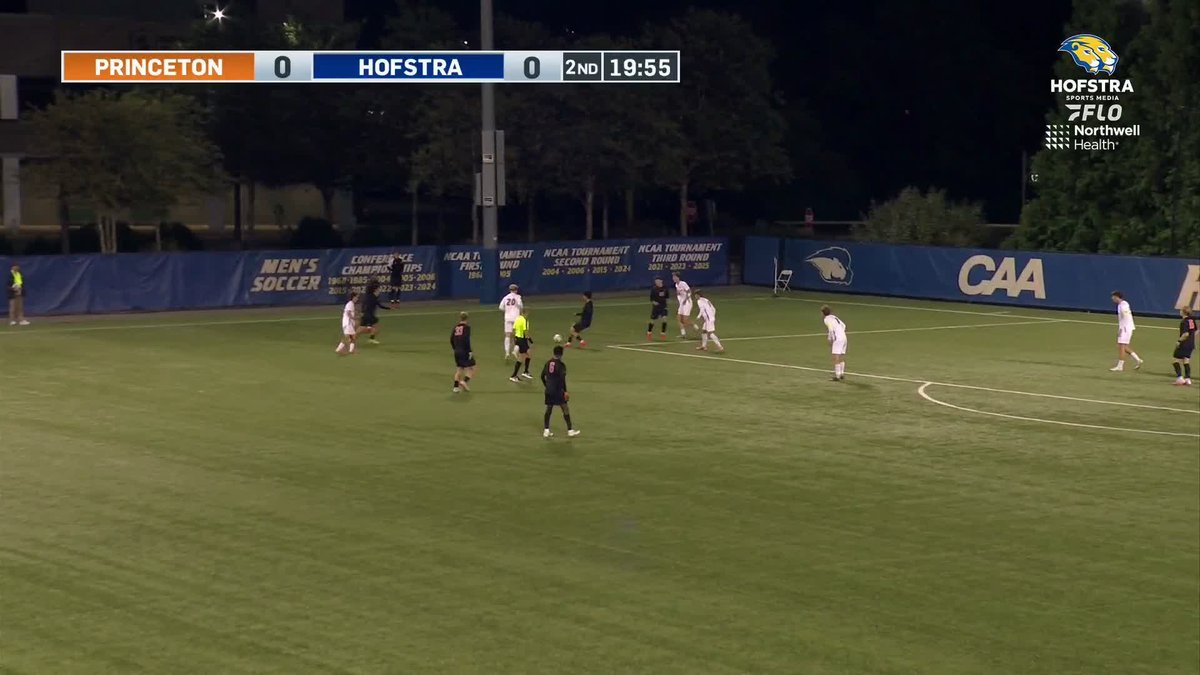A soccer match between Princeton and Hofstra shows the scoreboard indicating a 0-0 tie at 19:55 in the 2nd half, with players near the sideline banners showing conference championships and CAA branding.