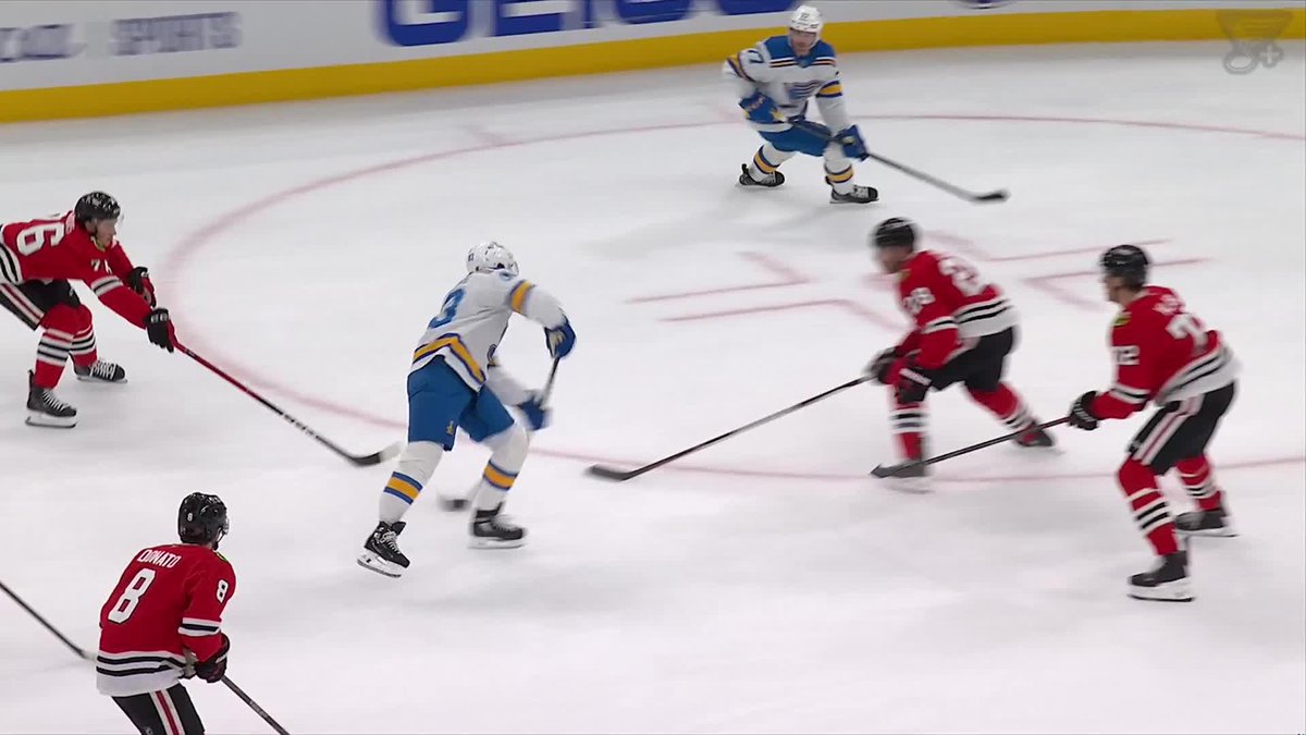 An NHL hockey game featuring players in blue St. Louis Blues jerseys and red Chicago Blackhawks jerseys competing on the ice, with player #8 Connato visible in the foreground.