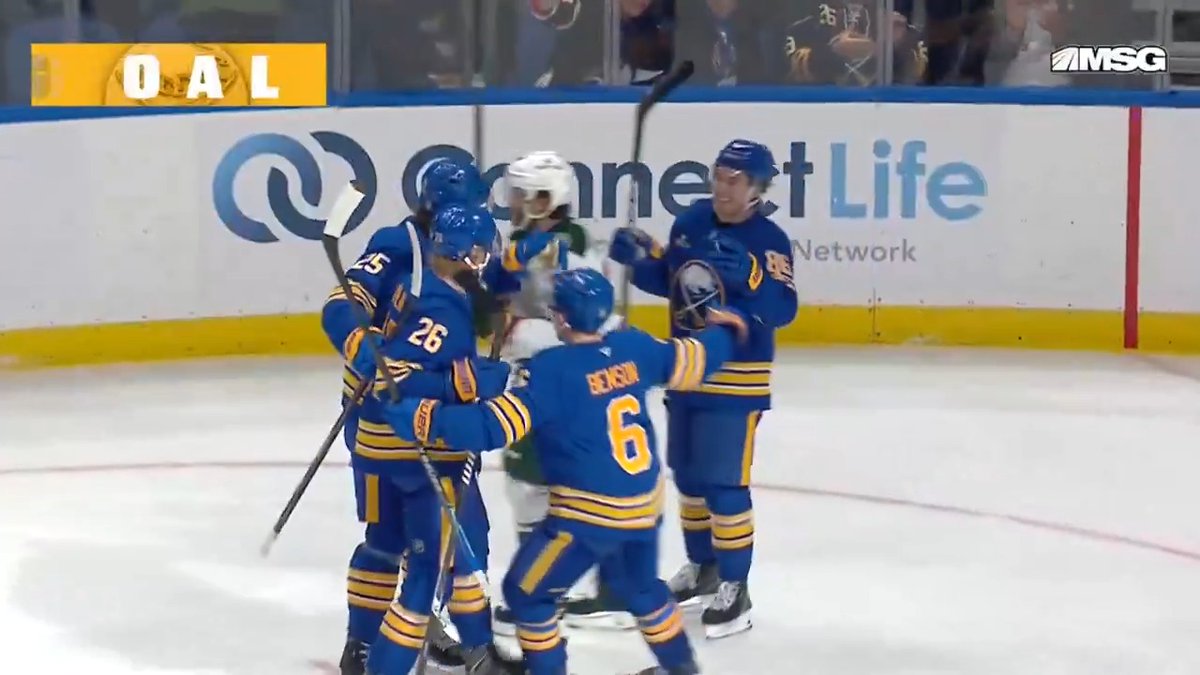 The Buffalo Sabres players, including numbers 26 and 6, celebrate together on the ice after a goal, as shown by the "GOAL" graphic on the MSG broadcast. The scene perfectly matches the "#LetsGoBuffalo" celebration as the team gathers near the boards to mark their successful play.