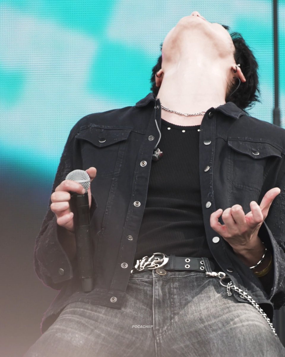 A performer wearing a black shirt and denim jacket holds a microphone while tilting their head back, with the watermark "POCACHIIP" visible.