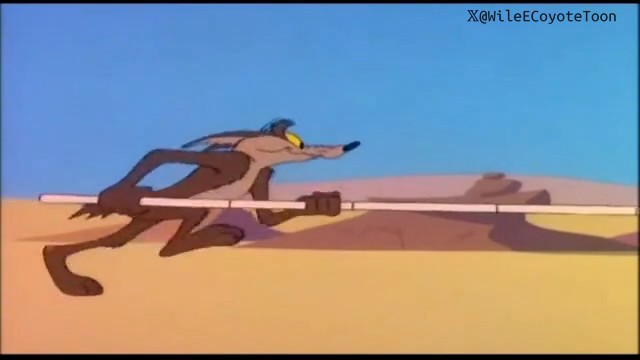 Wile E. Coyote sprints across the sandy terrain while gripping a long stick in both hands, using it as he attempts to chase down his elusive target. The watermark "X@WileCoyoteToon" appears in the top right corner, illustrating the cartoon character's resourceful use of the stick.