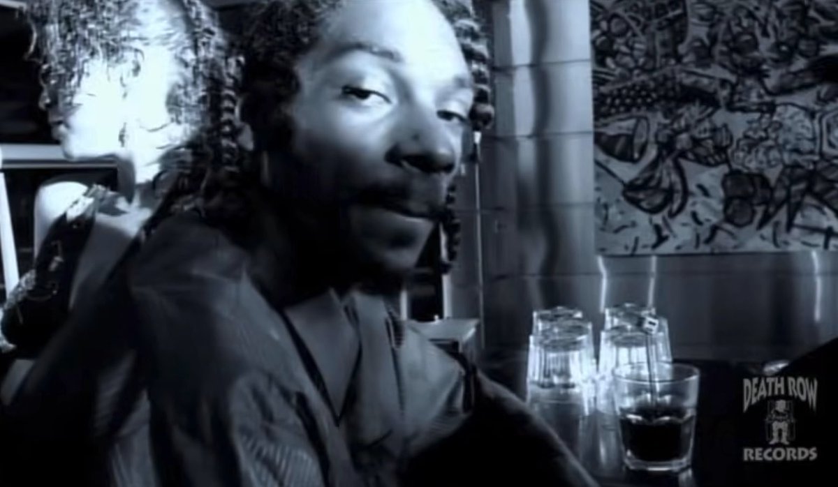 A black and white image featuring a double-exposure effect of a smiling face, with a "DEATH ROW RECORDS" logo in the bottom right corner.