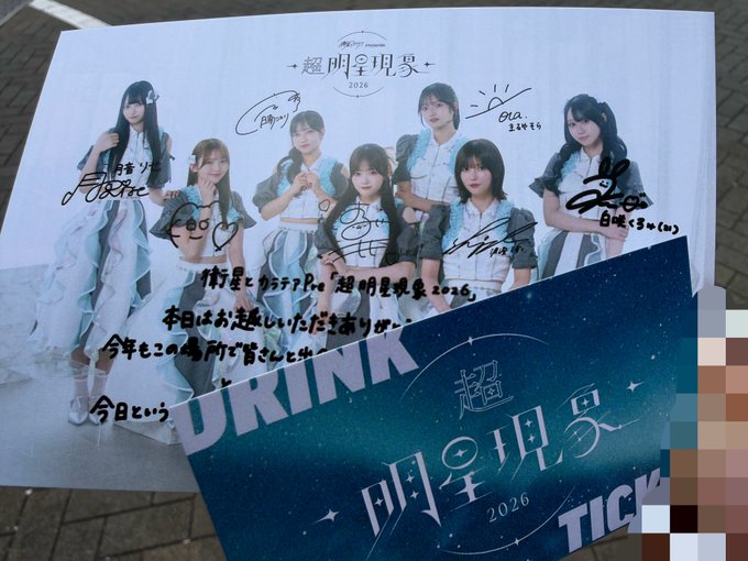 A signed promotional poster for '超明星現象 2026' (Cho Myojo Gensho 2026) features seven young women in matching outfits with handwritten signatures, placed above a matching ticket.