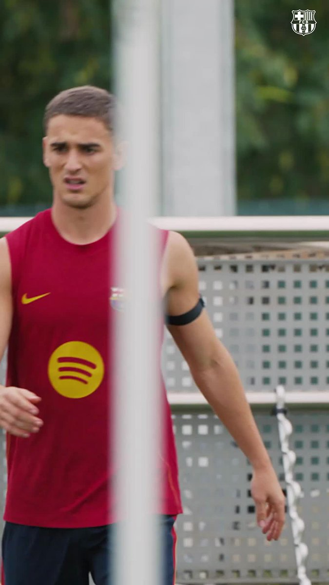 A young Barcelona player in a maroon sleeveless training kit with a yellow Spotify logo runs during a training session, with the FC Barcelona crest visible in the top right corner of the frame.