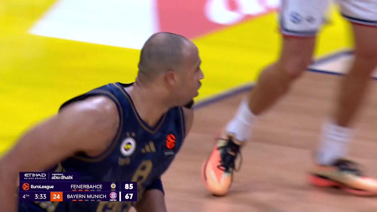 A bald Fenerbahçe basketball player in a dark blue jersey reacts intensely during a EuroLeague game against Bayern Munich, with the scoreboard showing Fenerbahçe leading 85-67 with 3:33 left in the 4th quarter.