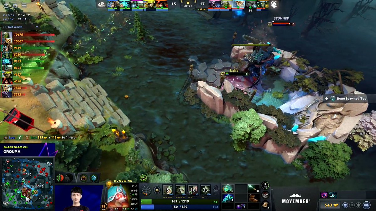 A Dota 2 gameplay screenshot showing the Hoodwink hero with a minimap, player stats, net worth chart, and a streamer's webcam feed in the bottom left, with a 'Movember' logo visible.
