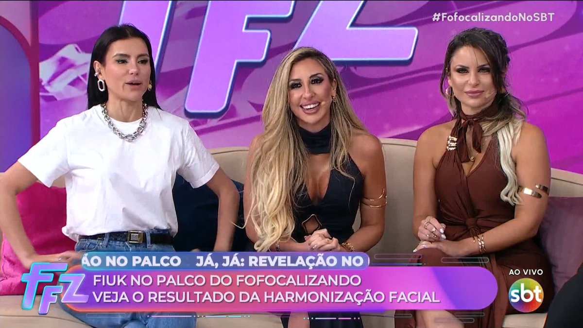 Three women appear on the Brazilian SBT television program "Fofocalizando," as indicated by the "#FofocalizandoNoSBT" hashtag in the top right corner. The on-screen text reads "AO NO PALCO - JÁ, JÁ: REVELAÇÃO NO FIUK NO PALCO DO FOFOCALIZANDO - VEJA O RESULTADO DA HARMONIZAÇÃO FACIAL," announcing an upcoming reveal of Fiuk's facial harmonization results.
