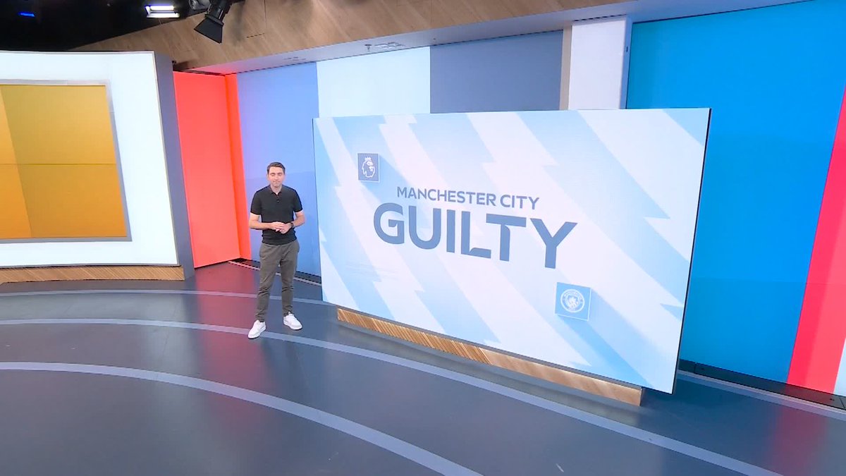 A presenter stands in a brightly colored studio next to a large screen displaying "MANCHESTER CITY GUILTY" alongside the Premier League logo, visually supporting the breaking news about the independent commission's verdict against the club.