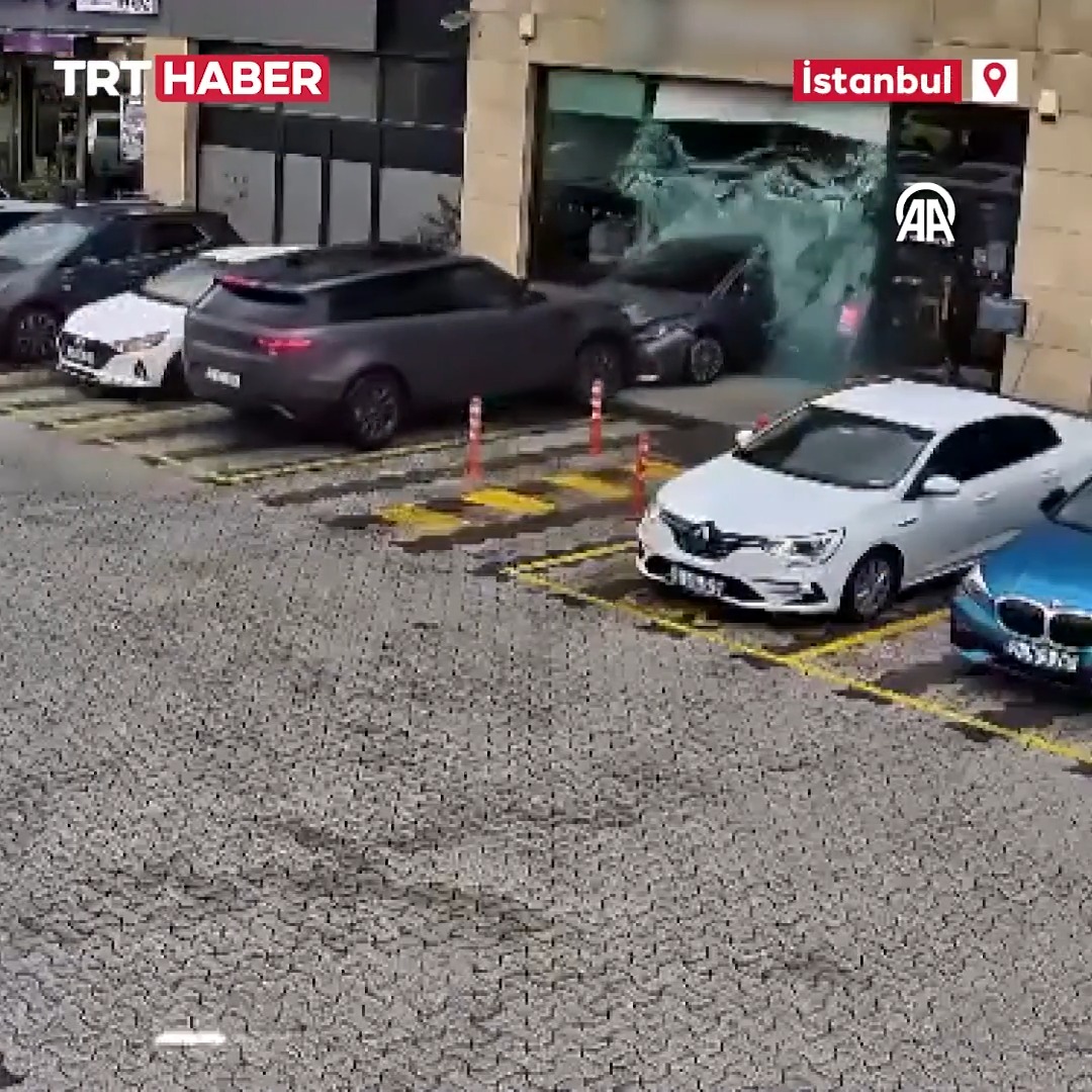 A news broadcast screenshot from TRT Haber in Istanbul shows a street scene where a car appears to have crashed through a storefront's glass window, with several vehicles visible in the parking area.