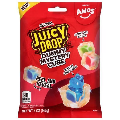 A red package of Amos Juicy Drop Gummy Mystery Cube candy, labeled 'NEW!', '90 CALORIES PER SERVING', and 'NET WT 5 OZ (142g)', showing a gummy cube being peeled to reveal a mystery character inside.