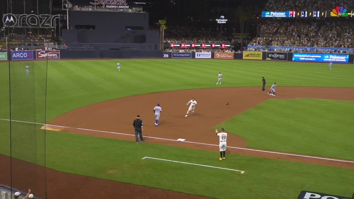 A player in a Dodgers uniform (#5) runs toward home plate as a Padres fielder chases a ground ball on the infield at Petco Park, with player #20 standing nearby. The image captures the moment when Fernando Tatis Jr. raced around the bases on a play at Petco Park, illustrating the post's reference to him "never stopped running."