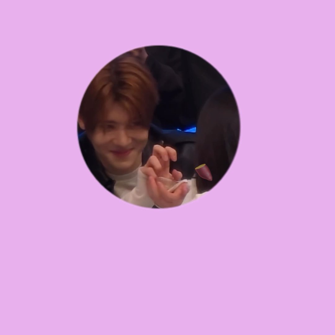 A circular profile picture with a light purple background shows a smiling young man with light brown hair making a finger heart gesture toward someone off-camera, capturing a sweet fan meeting moment. The post describes a fan who couldn't attend the 2nd anniversary event but received the idol's proposal and confession of "I like you," causing her to faint.