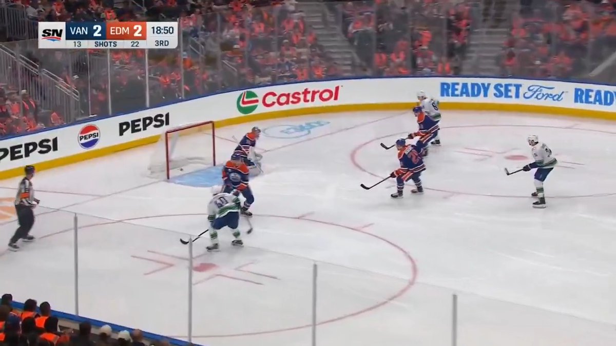 An NHL hockey game between Vancouver (VAN) and Edmonton (EDM) tied 2-2 in the 3rd period, shown on the SN broadcast with the Canucks players crowding Edmonton's net, appears to capture the moments leading up to Elias Pettersson's ("Lekkerimäki" or referred to as "LEK") laser shot. The Canucks player in white (#40) winds up his stick in front of the goal, setting up the precision snipe that would make it 3-2.