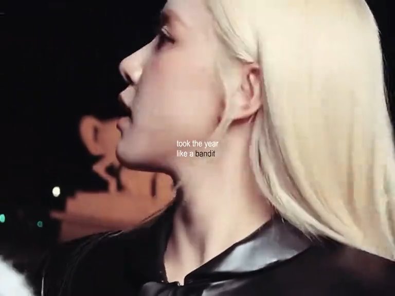 A side-profile close-up of a blonde woman wearing a black jacket at night, with the overlaid text "took the year like a bandit," which ties into the post's theme of an effortlessly powerful, year-defining presence.