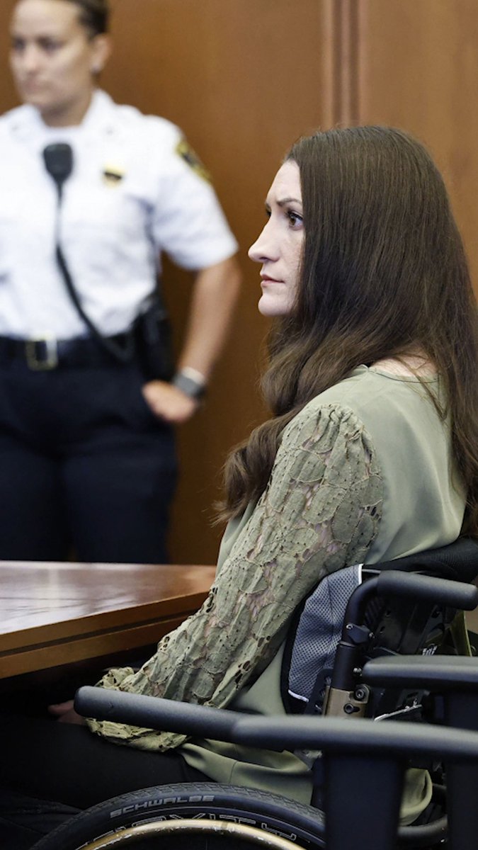 Lindsay Clancy sits in a wheelchair wearing an olive green top with lace sleeves during a court proceeding, with a uniformed officer standing behind her. The image accompanies a TMZ discussion about her potential release, highlighting her somber profile as she faces the legal proceedings that have gained significant public attention.