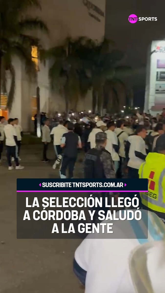 A nighttime crowd scene with a TNT Sports overlay and Spanish text reading 'LA SELECCIÓN LLEGÓ A CÓRDOBA Y SALUDÓ A LA GENTE', showing fans gathered with phone lights and security personnel in yellow vests.