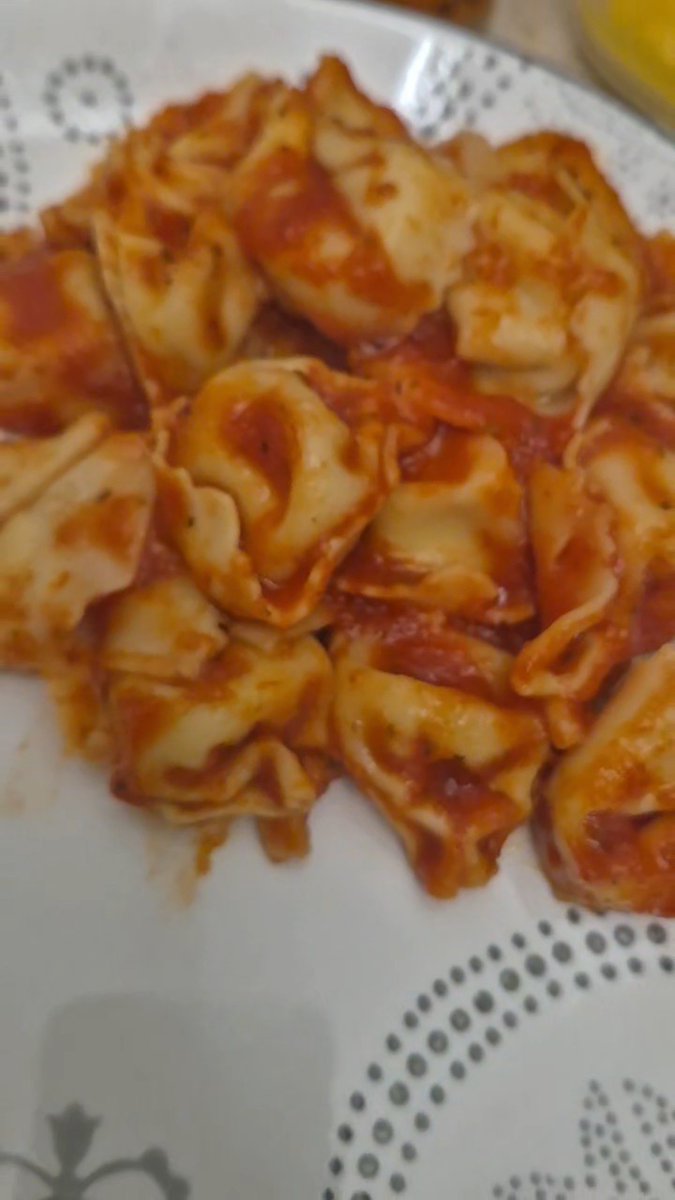 A plate of tortellini pasta covered in tomato sauce.