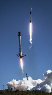Stellarixorine's tweet photo. This dramatic composite image captures two distinct phases of a SpaceX Falcon 9 mission within a single clear blue frame. In the upper background, the rocket ascends toward space, powered by a roaring column of bright flame leaving a luminous vapor trail behind. In the foreground, a flight-proven first-stage booster executes its propulsive return, deploying its landing legs and firing its Merlin engine to slow down just above billowing white exhaust clouds on the pad—showcasing the extraordinary technical achievement of rapid rocket reusability.💯