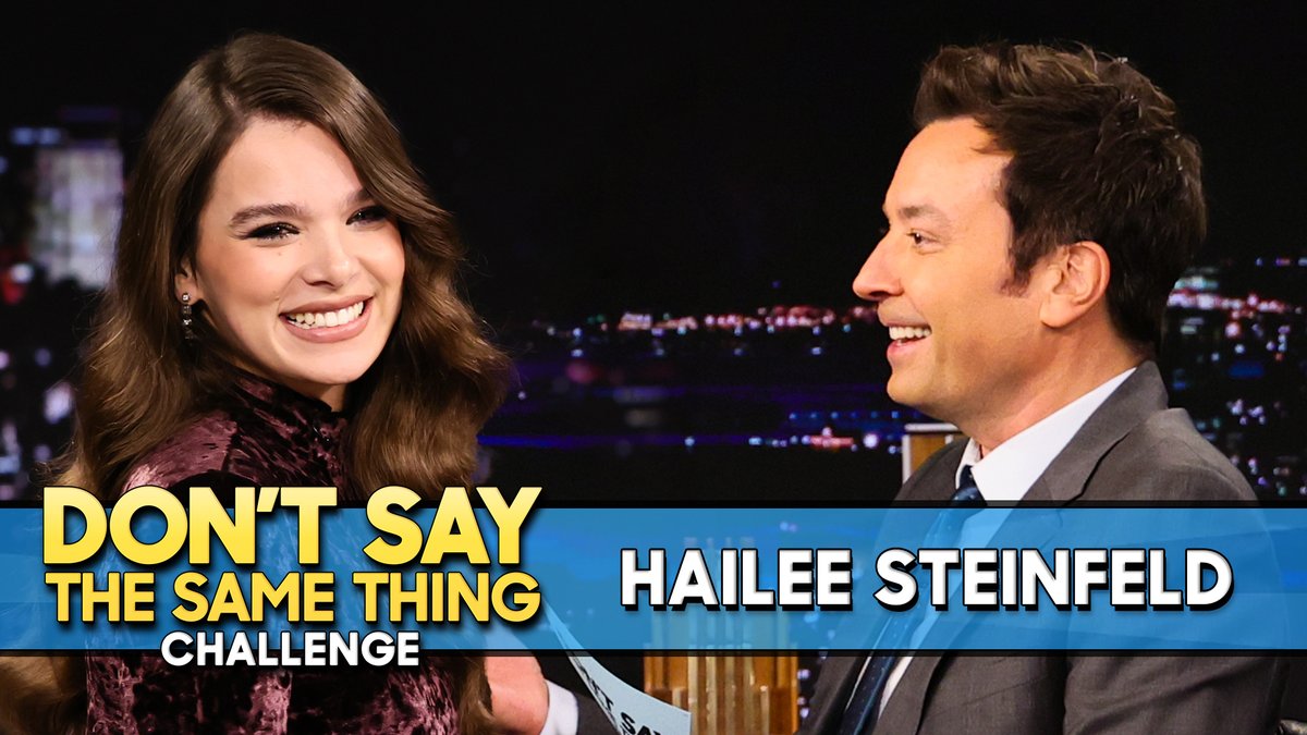 Hailee Steinfeld and Jimmy Fallon laugh together on a late night talk show stage, with on-screen graphics reading "DON'T SAY THE SAME THING CHALLENGE" and "HAILEE STEINFELD" displayed against a city skyline backdrop.