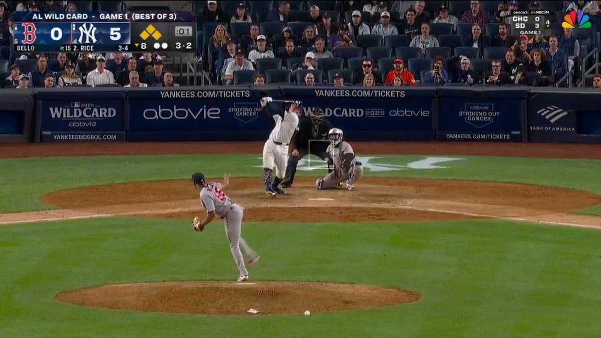 A Red Sox pitcher delivers to Yankees batter Ben Rice, who has just completed a powerful swing at Yankee Stadium. The scoreboard shows the Yankees up 5-0 over the Red Sox in the bottom of the 8th inning, with bases loaded (3 yellow diamonds) and a 3-2 count on Rice—capturing the exact moment of his grand slam in the AL Wild Card Game 1.