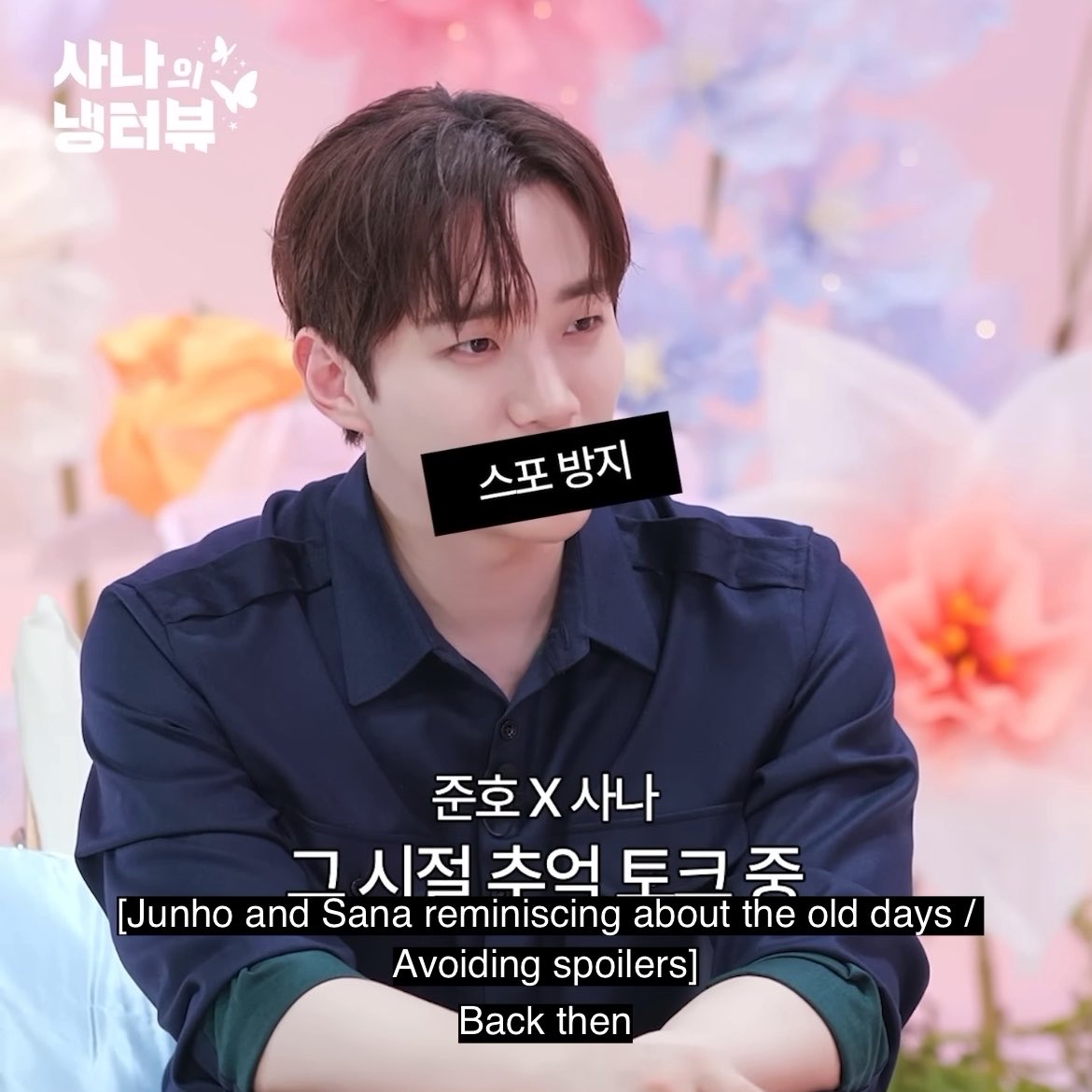 A man in a dark shirt sits against a floral backdrop with Korean text overlays, including "사나의 냉터뷰," "스포방지," "준호 X 사나 그 시절 추억 토크 중," and English subtitles reading "Junho and Sana reminiscing about the old days / Avoiding spoilers / Back then."