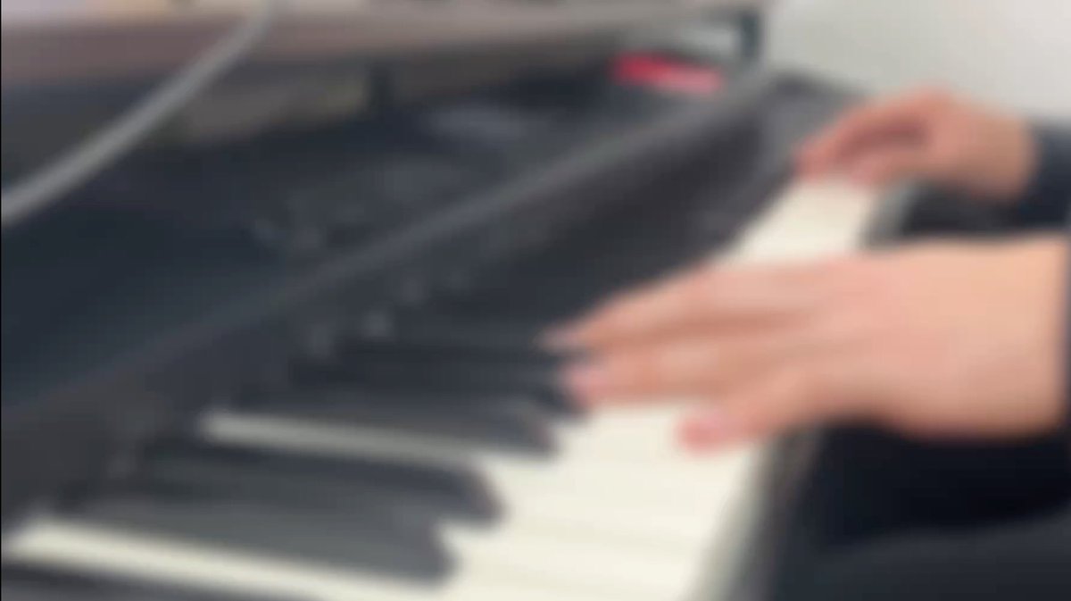 A blurry image shows hands playing a keyboard or piano.