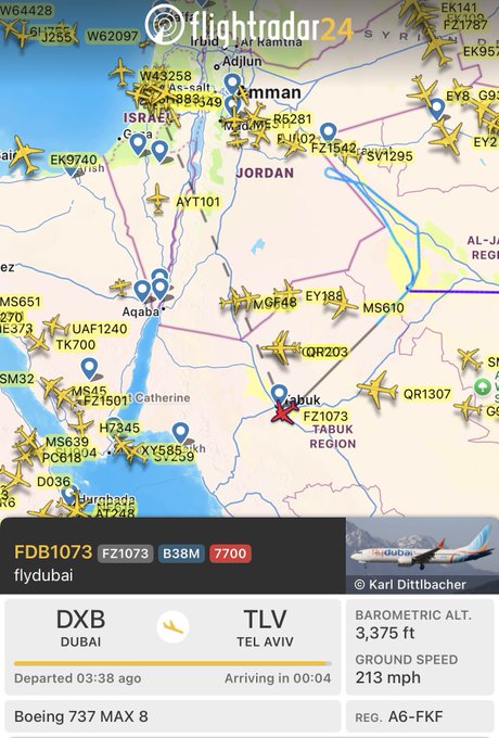 A flight tracking app displays flydubai flight FZ1073 from Dubai (DXB) to Tel Aviv (TLV), currently squawking emergency code 7700 at 3,375 feet altitude. The post notes the Boeing 737 MAX 8 (registration A6-FKF) is circling in Saudi airspace with intermittent transponder coverage, indicating a developing emergency situation.