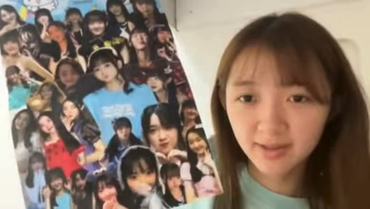 A young woman with bangs speaks to the camera in a selfie-style video, holding up a poster or collage covered in cut-out photos of various people.