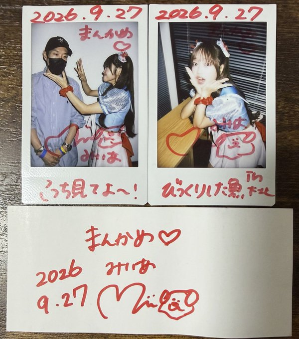 Two printed photos dated "2026.9.27" feature a woman in a blue-and-white outfit posing playfully with fans, decorated with red marker messages like "まんかめ♡," "ばいばー," and "はなまる," accompanied by a handwritten note reading "まんかめ 2026.9.27 Mila♡." This matches the post about encountering a cute performer ("みいあキャット") during the TRIGGER→ support event at HNG SONIC 2026 Flowers Loft in Shimokitazawa, where the fan was too nervous to look them in the eyes or hold a proper chat, prompting the churippu/2-shot service as a memento.
