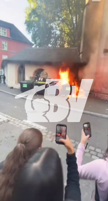 People filming a fire on a street with their smartphones, with a "BV" watermark visible.