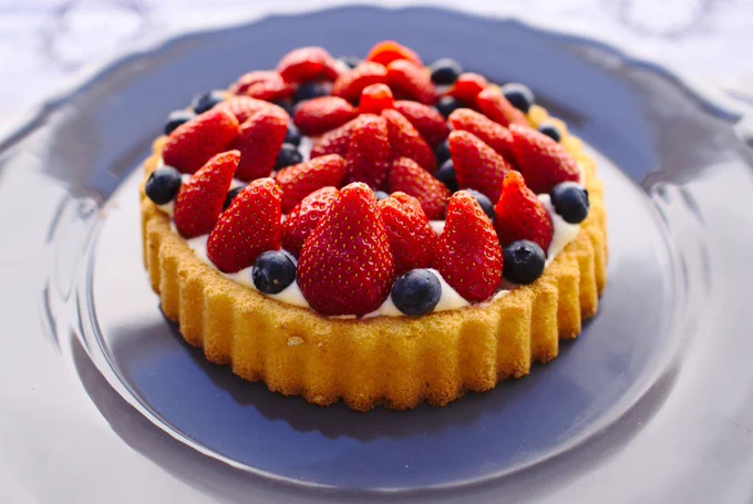 A tart with yogurt, blueberries and strawberries, sitting on a blue plate. 