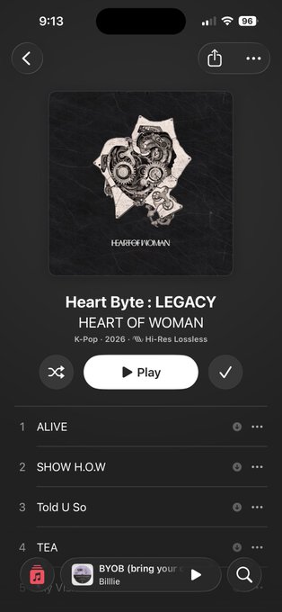 A mobile music player screen displays the K-Pop 2026 album 'Heart Byte: LEGACY' by HEART OF WOMAN, showing tracks like 'ALIVE', 'SHOW H.O.W', 'Told U So', and 'TEA'.