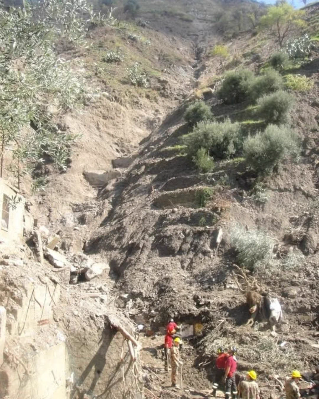 Soccorritori in azione ai piedi di un pendio scosceso devastato da una frana.