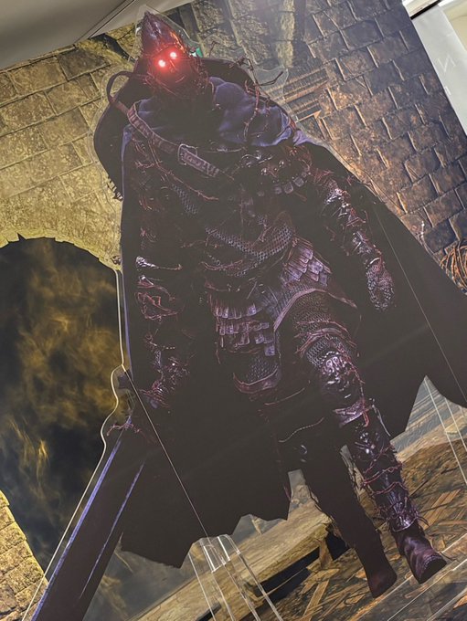 A dark fantasy figurine of a knight in ornate black armor with a glowing red eye stands displayed, featuring a pointed helmet and a flowing cape.