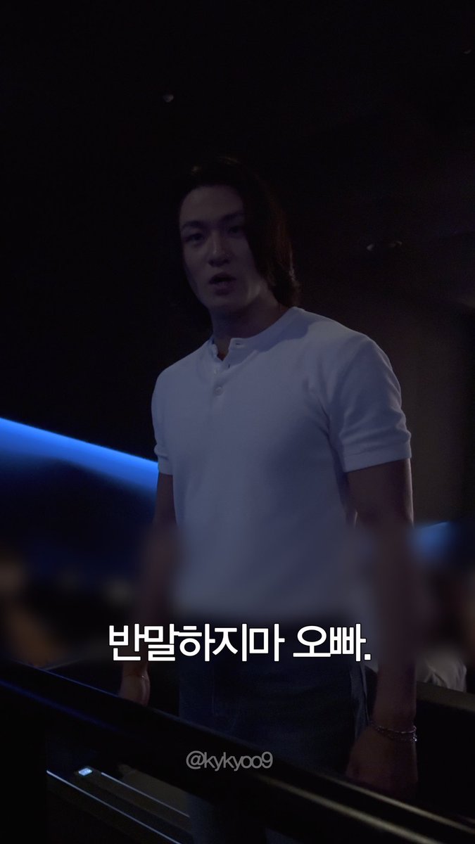 A young man with long hair wearing a white henley shirt stands in a dimly lit room with Korean text overlay reading "반말하지마 오빠." and a watermark "@kyky009".