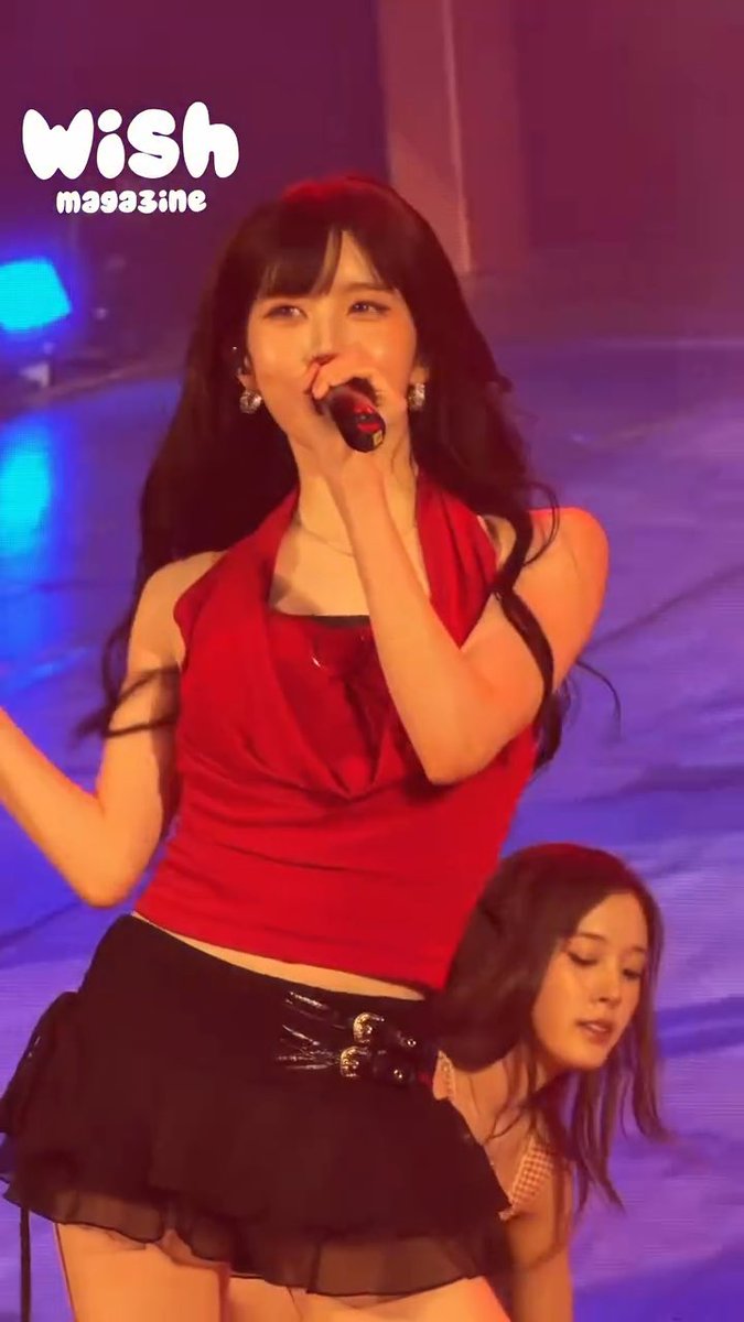 A female performer in a red halter top sings into a microphone on a stage with purple and blue lighting; the 'wish magazine' logo is visible in the upper left.