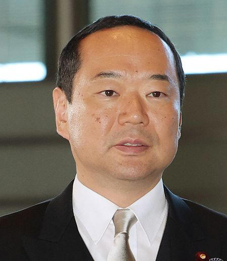 A close-up portrait of a Japanese man in a dark suit with a silver tie, identified by the accompanying post as Fujii Hayanuki, the newly appointed Minister of Internal Affairs and Communications who is facing allegations of paying local council members for poster-placement work.