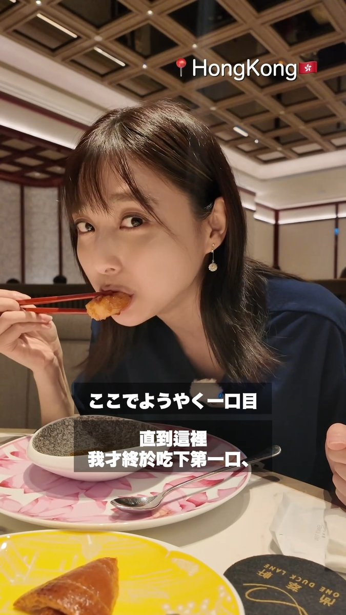 A woman eating with chopsticks in a Hong Kong restaurant, with subtitles reading 'ここでようやく一口目' and '直到這裡 我才終於吃下第一口'.